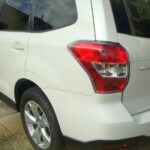 Before and after photographs of a damaged white Subaru that was repaired by Elite Paint & Body Shop in West Palm Beach, Florida
